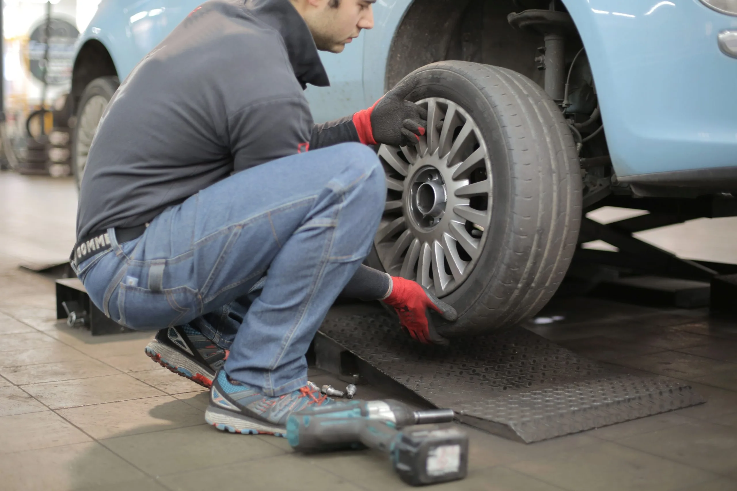 guy-changing-tire-scaled Towing in Eugene - flat tire repair on a blue colored car